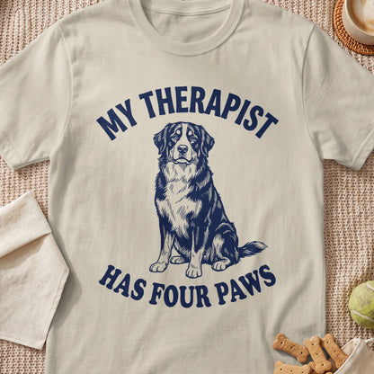 Light tan t-shirt with a graphic of a dog and text that reads "MY THERAPIST HAS FOUR PAWS".