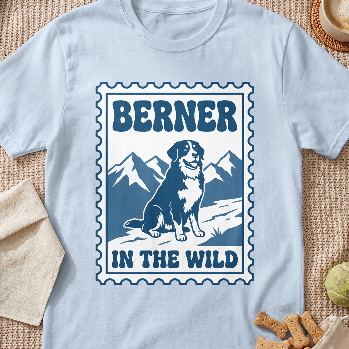 Bernese Mountain Dog sitting in front of mountains with text "BERNER IN THE WILD".