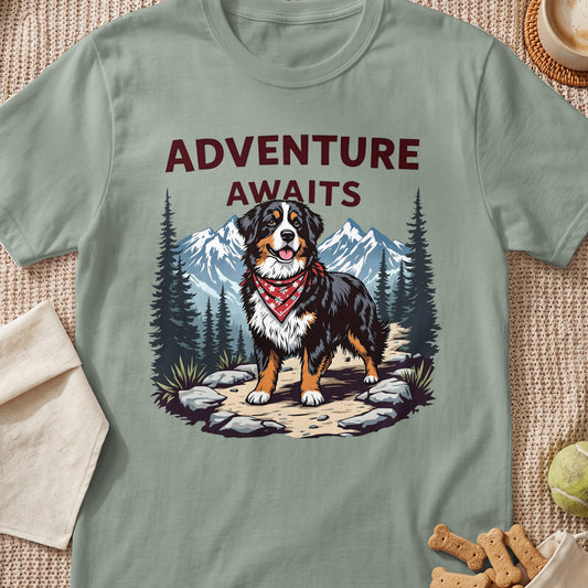 Bernese Mountain Dog with bandana on path, mountains, trees, and text "ADVENTURE AWAITS".