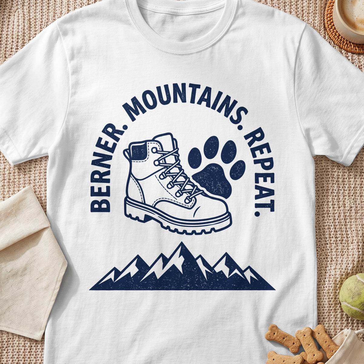 White t-shirt with navy graphic: hiking boot, paw print, mountains, and text.