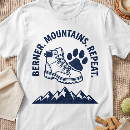 White t-shirt with navy graphic: hiking boot, paw print, mountains, and text.