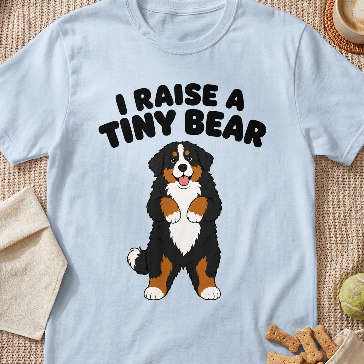 Light blue t-shirt with text "I RAISE A TINY BEAR" above cartoon Bernese Mountain Dog.