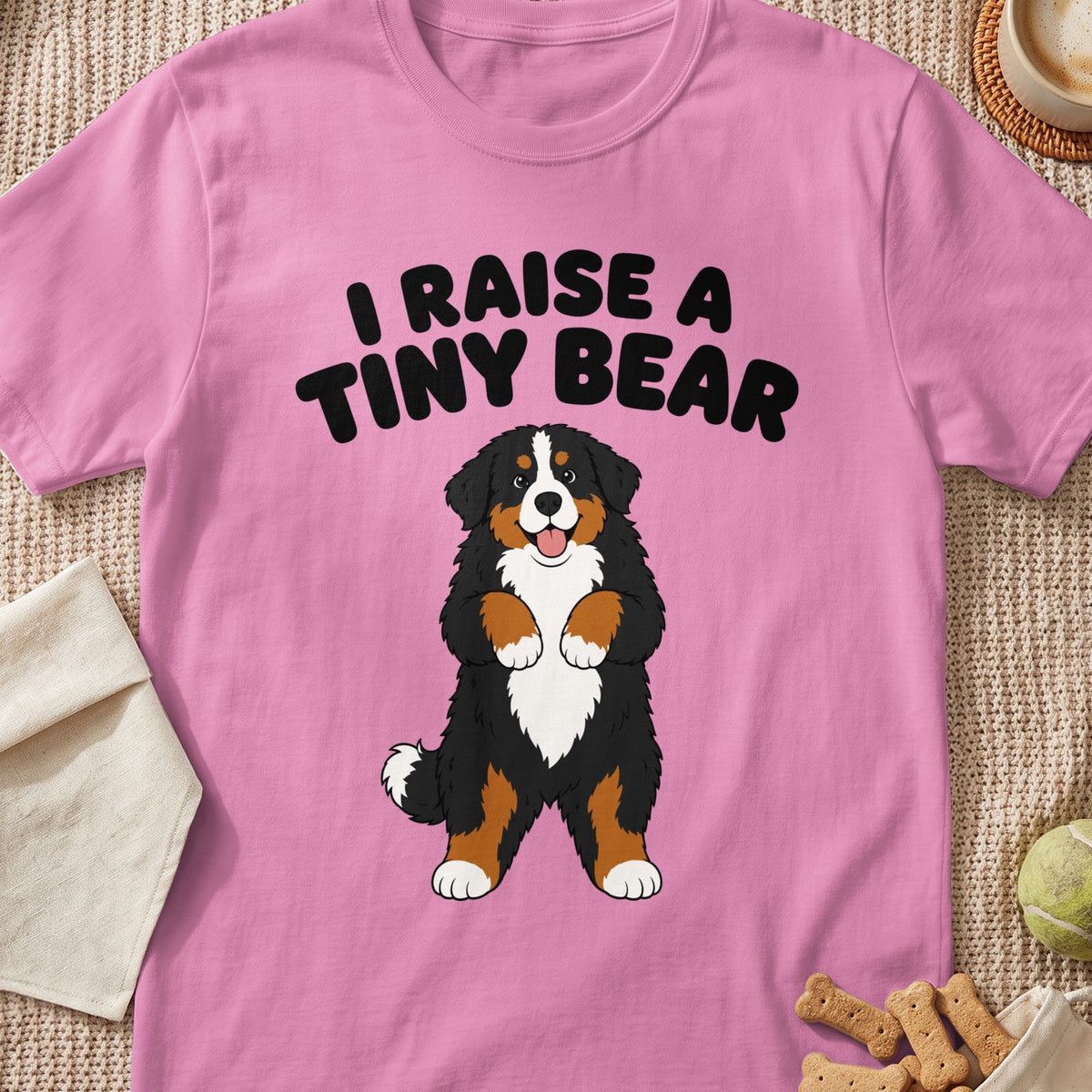 Pink t-shirt with black text "I RAISE A TINY BEAR" above a cartoon Bernese Mountain Dog.