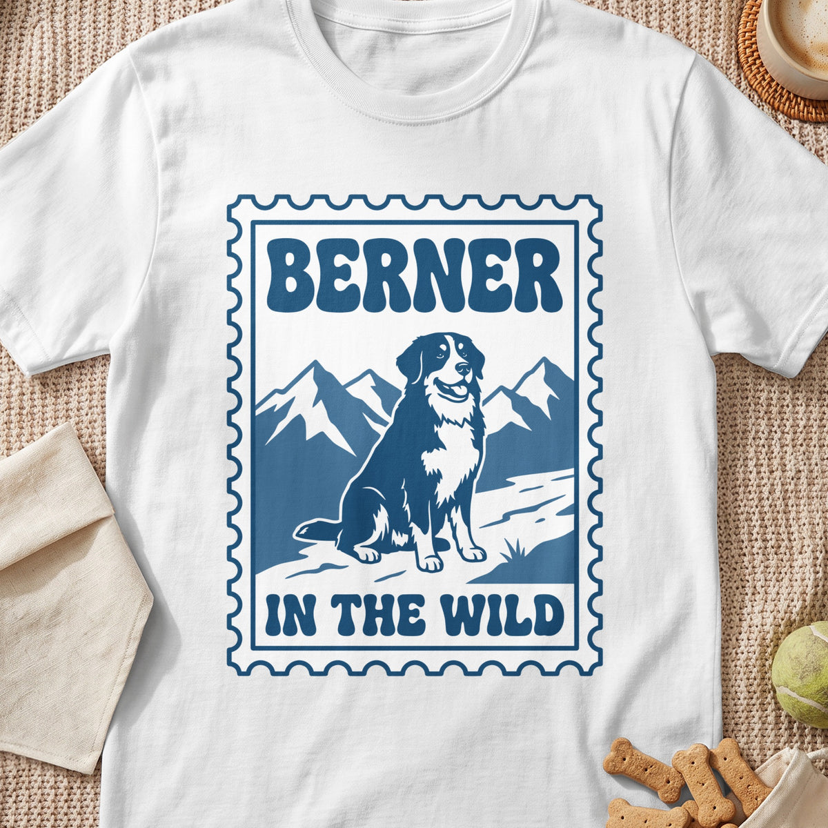Bernese mountain dog sitting in front of mountains with text "BERNER IN THE WILD"