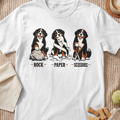 Bernese Mountain Dogs play rock, paper, scissors with a rock, toilet paper, and scissors.