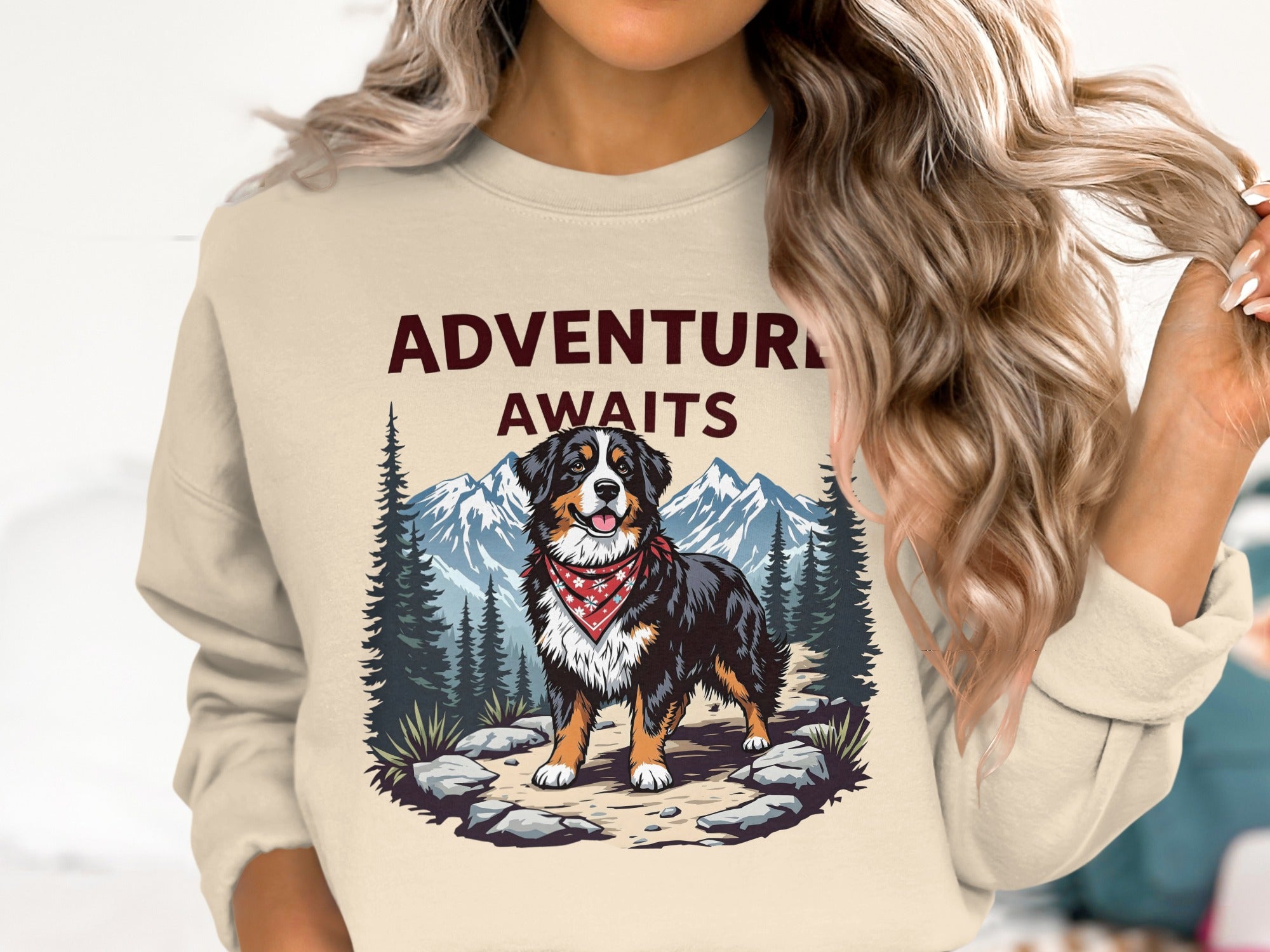 Bernese Mountain Dog wearing bandana on rocky path with pine trees and mountains; "ADVENTURE AWAITS" text.