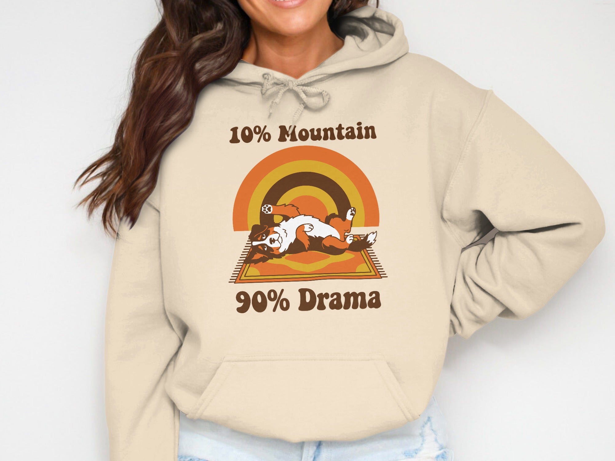 Beige hoodie with a retro graphic of a dog on a rug and text: "10% Mountain".