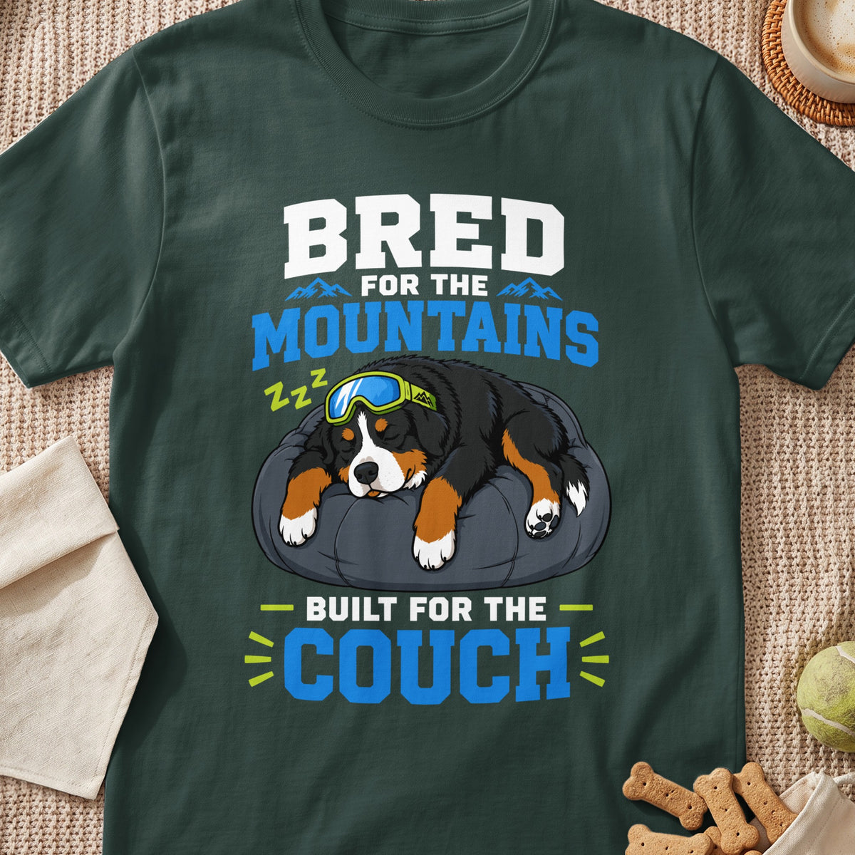 Bernese Mountain Dog wearing goggles sleeping on a pillow with text "Bred for the Mountains Built for the Couch".